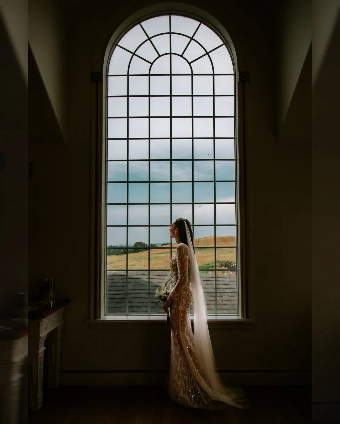 A bride at the arched window with the valley beyond