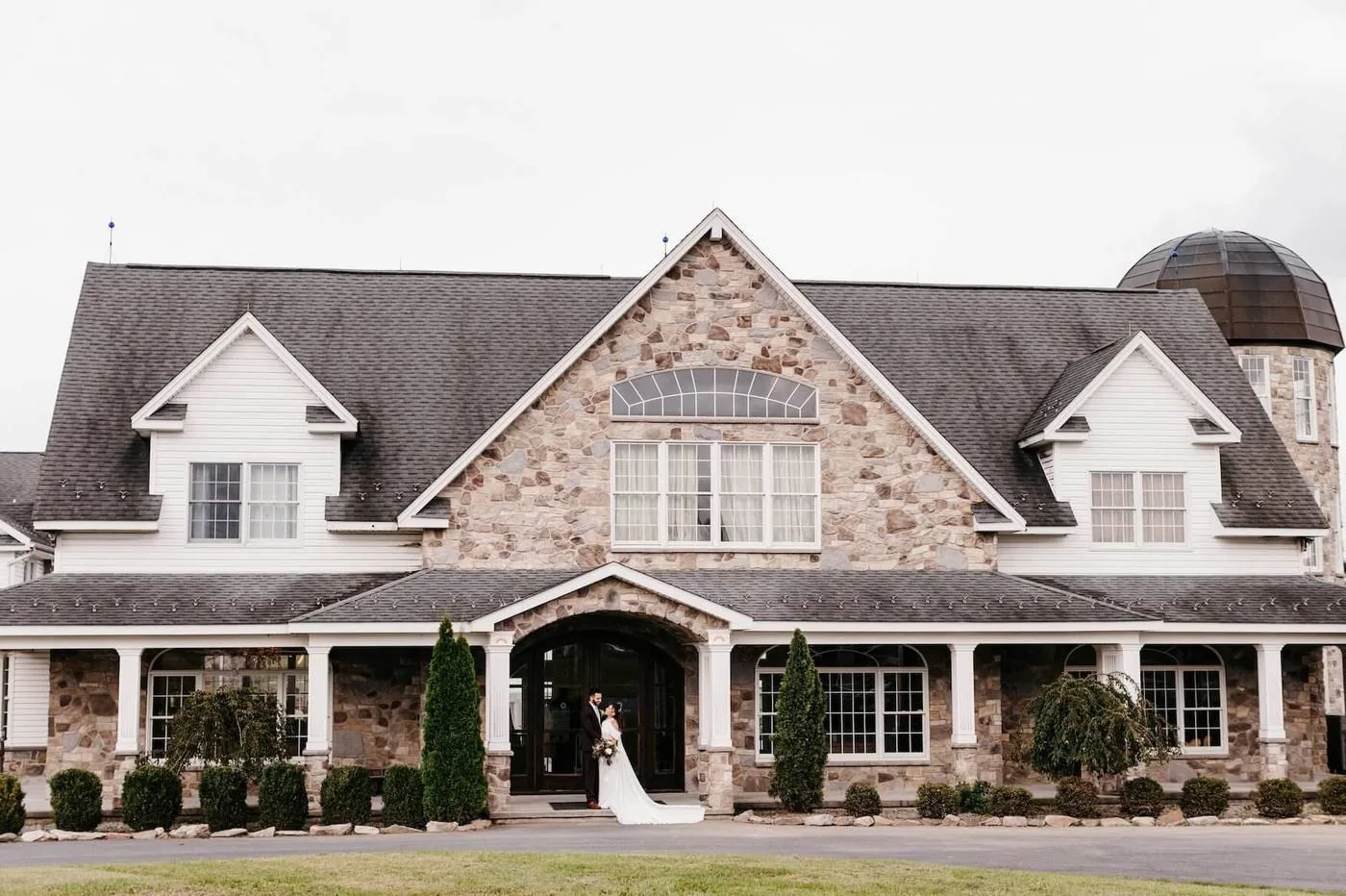 A couple at the front door of the stone mansion