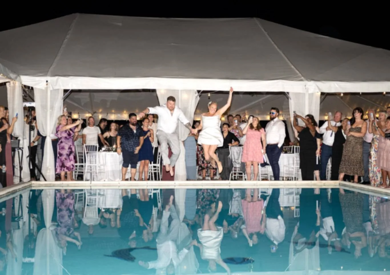 The couple jumping into the pool as guests cheer