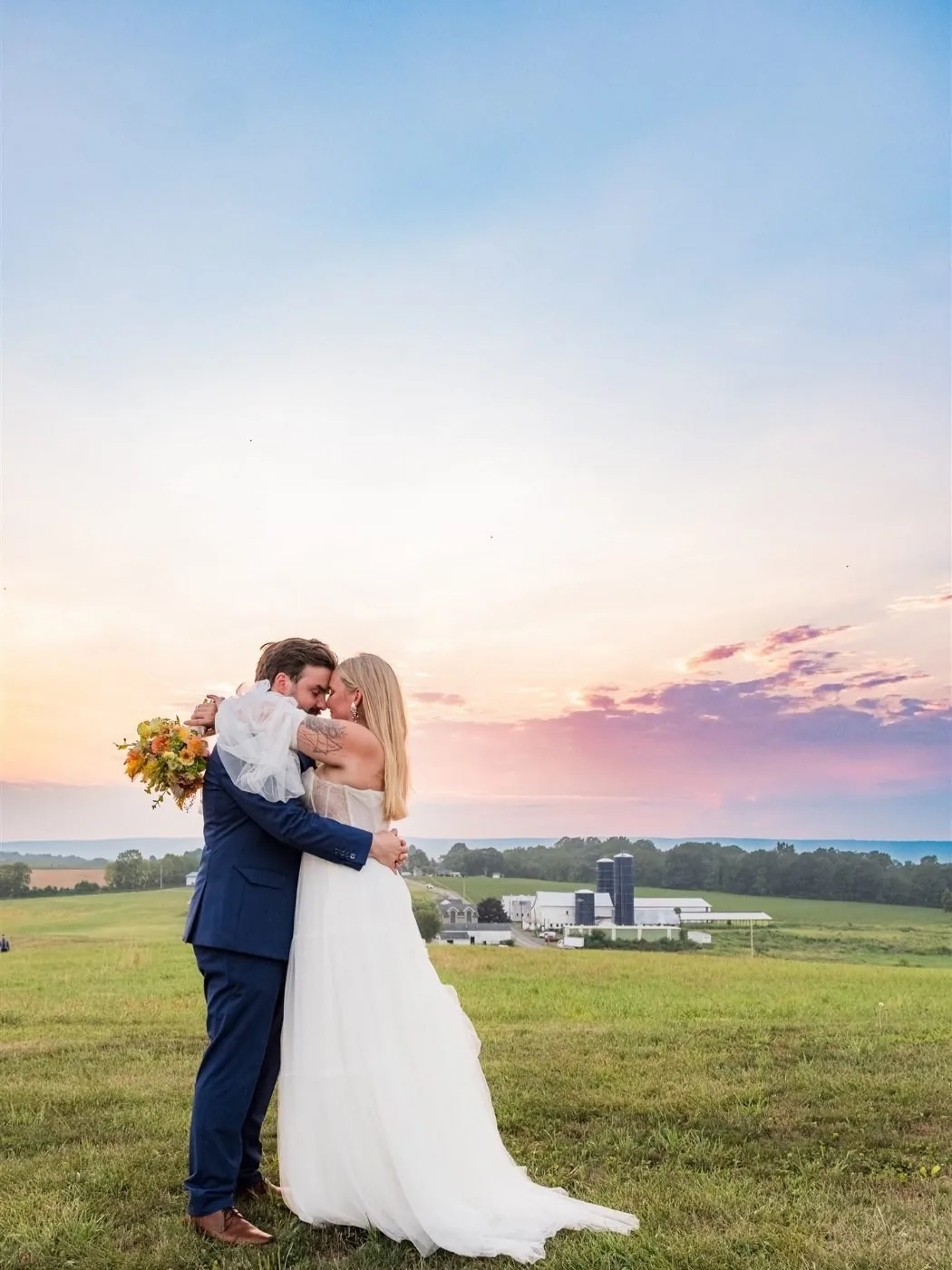 A couple kissing on the hilltop at sunset with the estate below